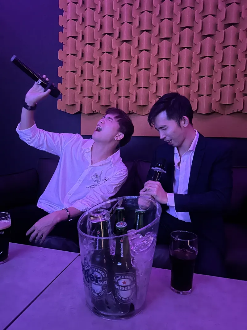 Two friends singing a karaoke duet in a private KTV room at Major 99, ice bucket on the table
