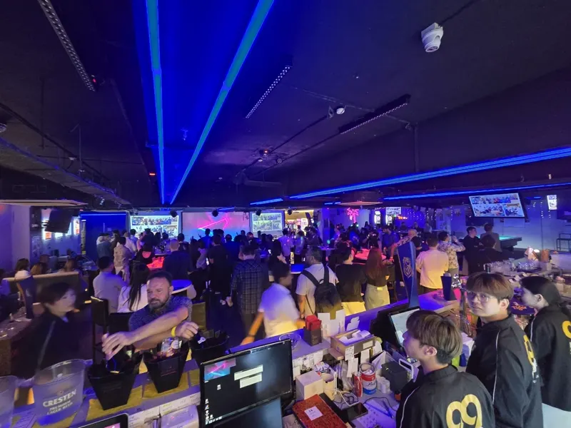 Major 99 staff in gold 99 jackets working the bar on a packed event night