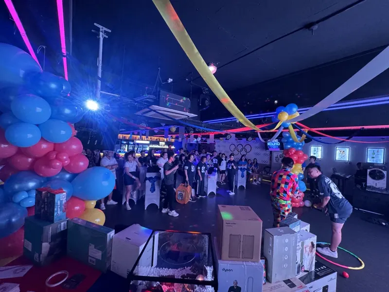 An Olympic-themed company Dinner and Dance in the Major 99 main hall, with balloon arches, games in progress and a prize table